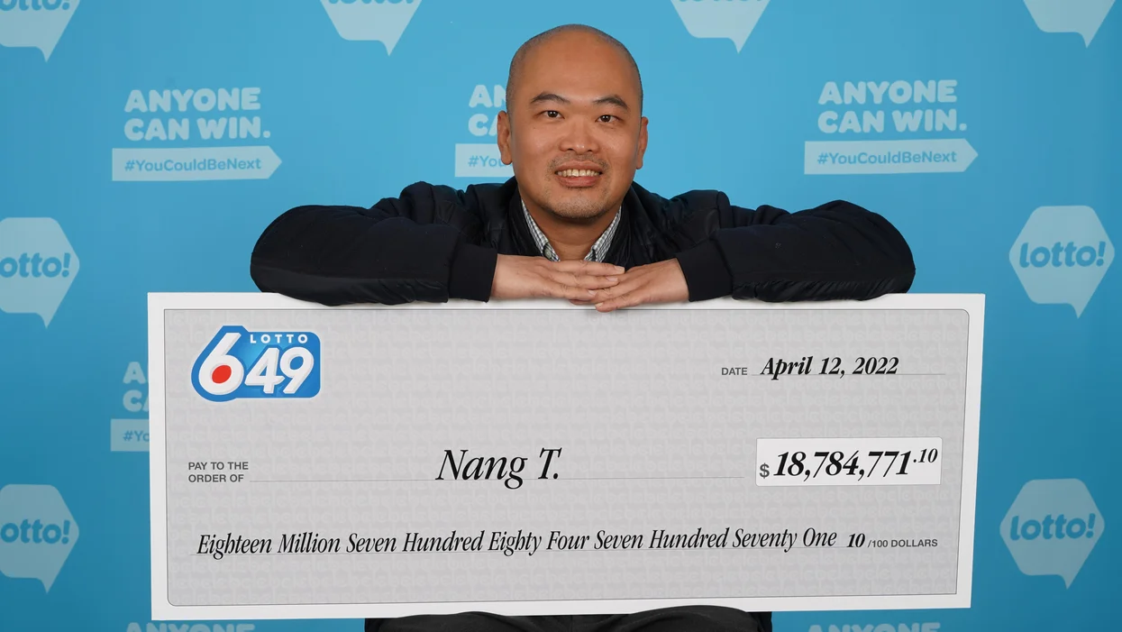 Nang (Paul) Trinh holding his Lotto 6/49 cheque for $18.7 million. (Source: BCLC)